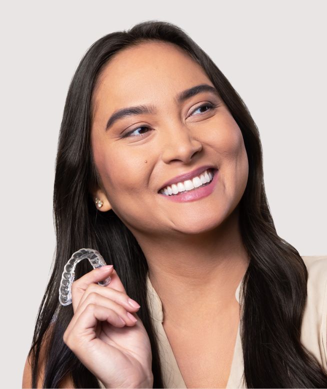 Woman smiling while holding a Chomper Labs night guard.