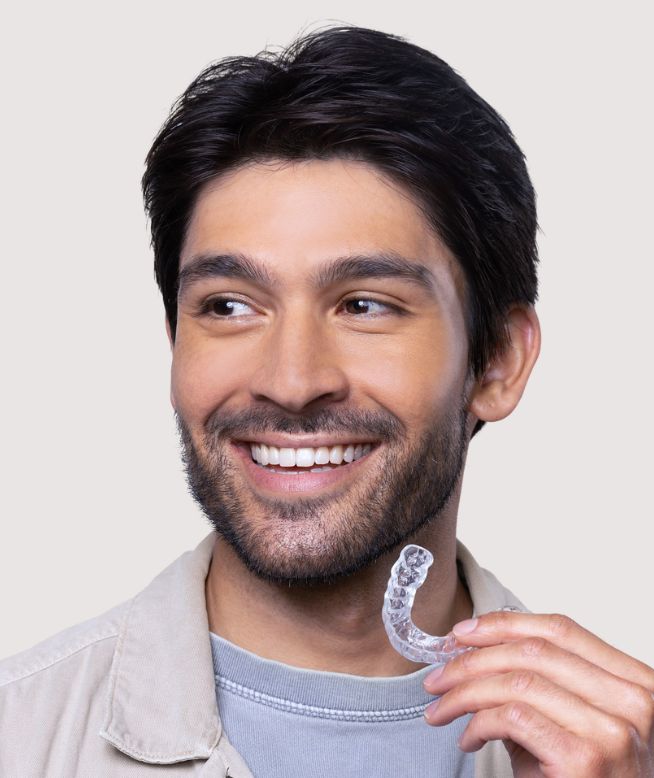 Man smiling while holding a Chomper Labs night guard.