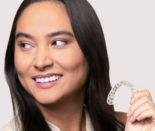 Woman smiling while holding a Chomper Labs night mouth guard.