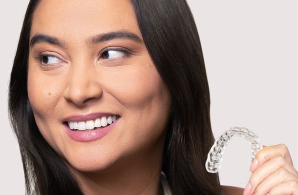 Woman smiling while holding a Chomper Labs night mouth guard.