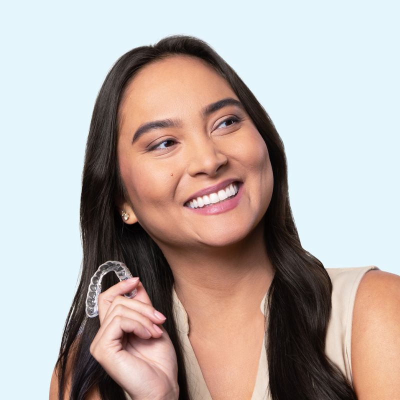 Woman smiling and holding a Chomper Labs night guard.